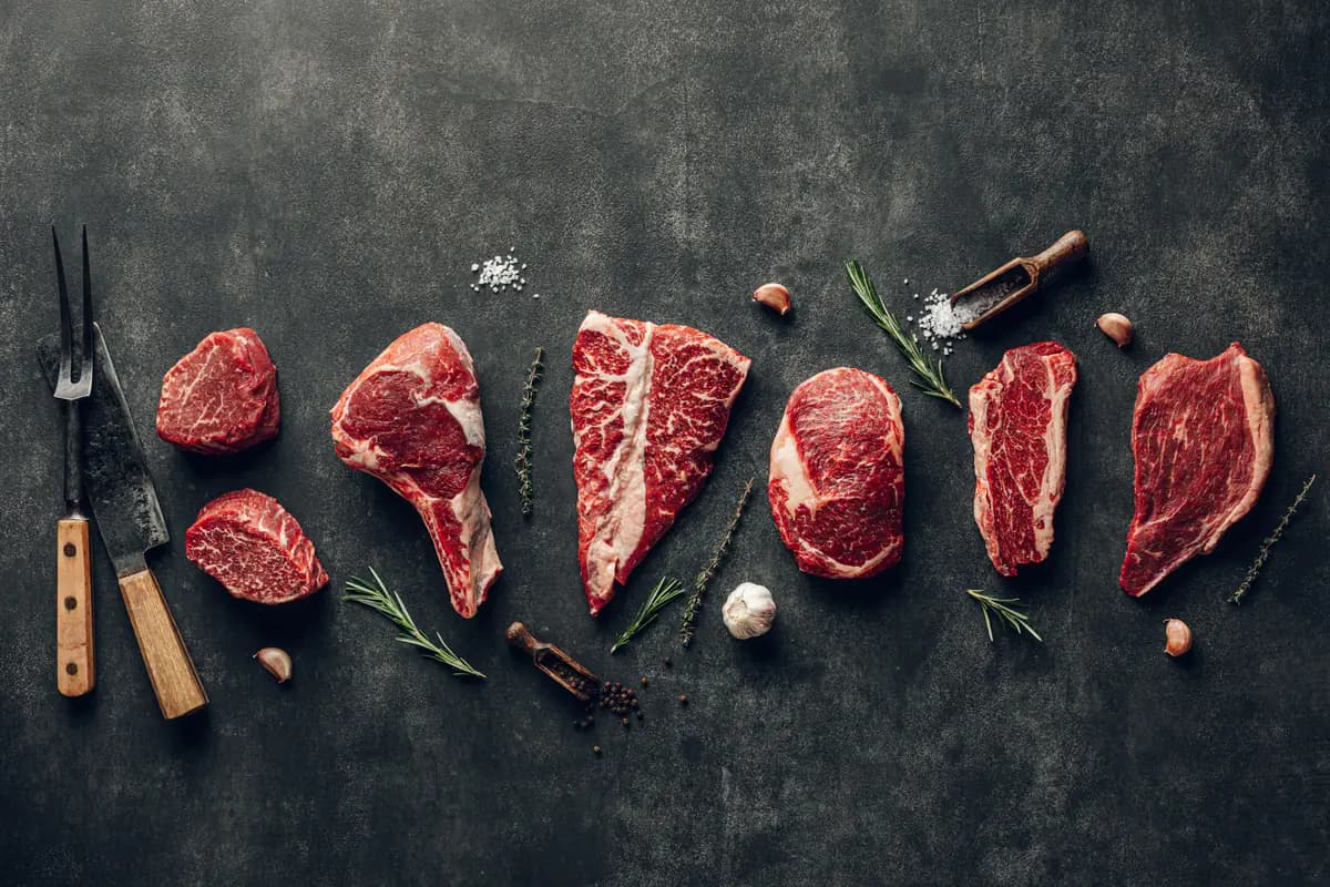 Raw beef cuts laid out on dark slate
